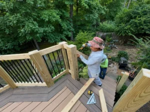 Worker finishing a gray composite deck corner with black metal balusters