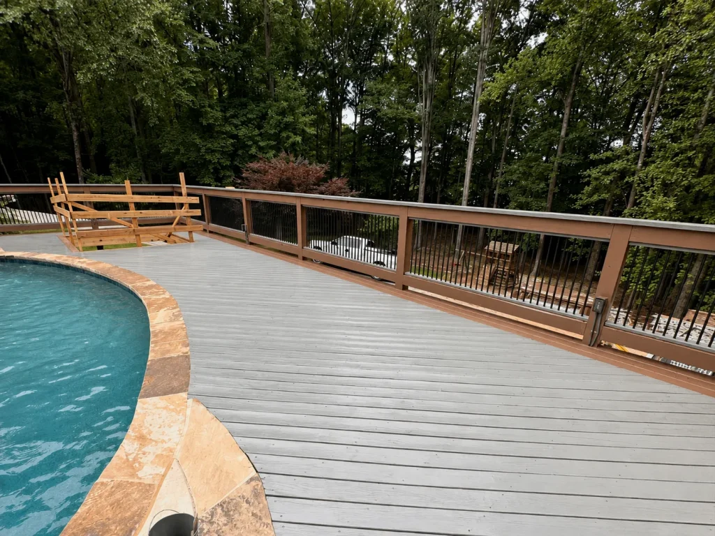 Gray composite pool deck with wood rails and black metal balusters