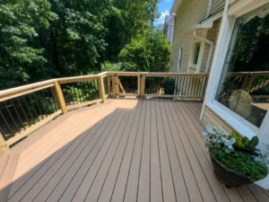Finished gray composite deck with natural wood railings beside a house