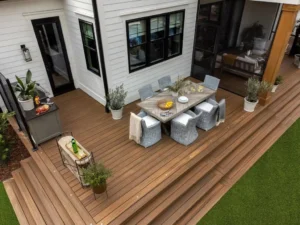 Multi-level brown composite deck with an outdoor dining area beside a white home