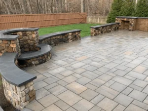 Spacious gray paver patio with curved stone seating walls and a built-in outdoor counter