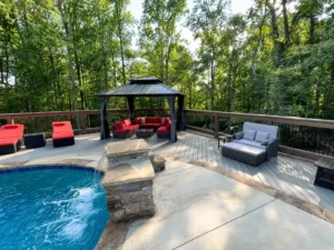 Pool deck with wood railings, a black gazebo, and red outdoor seating