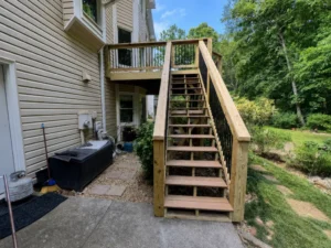 Upper wood deck with a tall exterior staircase behind a two-story home